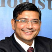 A professional portrait of a smiling man wearing glasses, a suit, and a red tie.