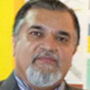 A man with a beard and mustache, wearing a dark grey suit, with a friendly expression, posed for a close-up portrait.