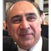 A middle-aged man with a friendly smile, wearing a black suit and tie.