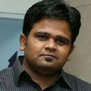 A man in a black shirt with short hair, smiling slightly and looking directly at the camera.