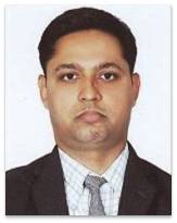 A professional portrait of a male individual dressed in a formal suit with a tie, looking serious and composed.