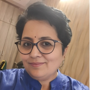 A portrait of a woman with short hair, wearing glasses and a blue top, smiling at the camera.