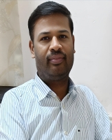 Portrait of a man wearing a striped shirt, sitting and looking directly at the camera.