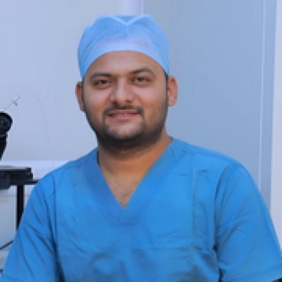 A smiling medical professional wearing blue scrubs and a surgical cap.